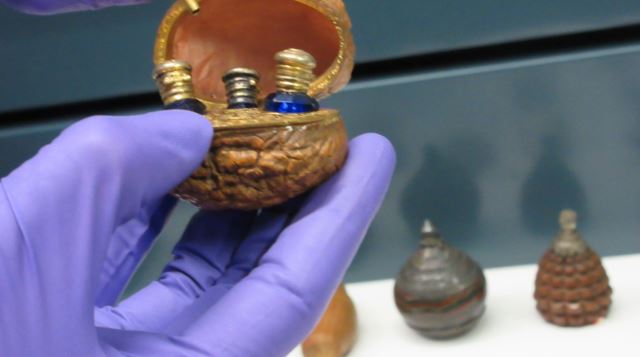 Walnut shell perfume case with three small bottles and a refilling funnel.