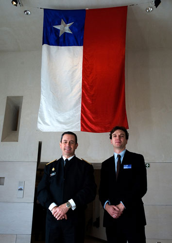 Admiral Edmundo Gonzalez, Commander-in-Chief of the Navy of Chile and lead curator Stuart Allan with the ensign from the Almirante Cochrane. 