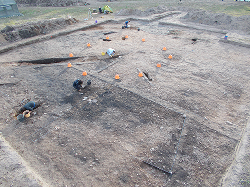 Our big roundhouse, with the natty orange buckets marking where posts once stood. You can see where we’ve dug through the hollow where the cattle were once kept.