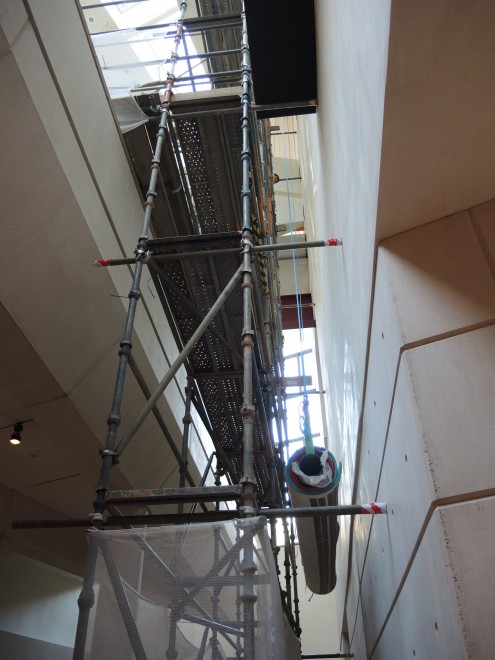 The rolled tapestry being lifted to the top of the scaffold