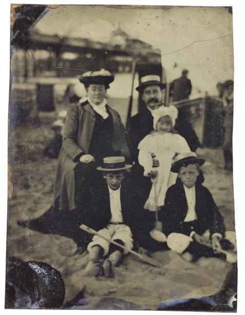 1/6 plate tintype, depicting a family group of parents, two boys and a young girl on a beach, possibly Margate jetty in the background, by an unknown photographer, 1880s - 1890s