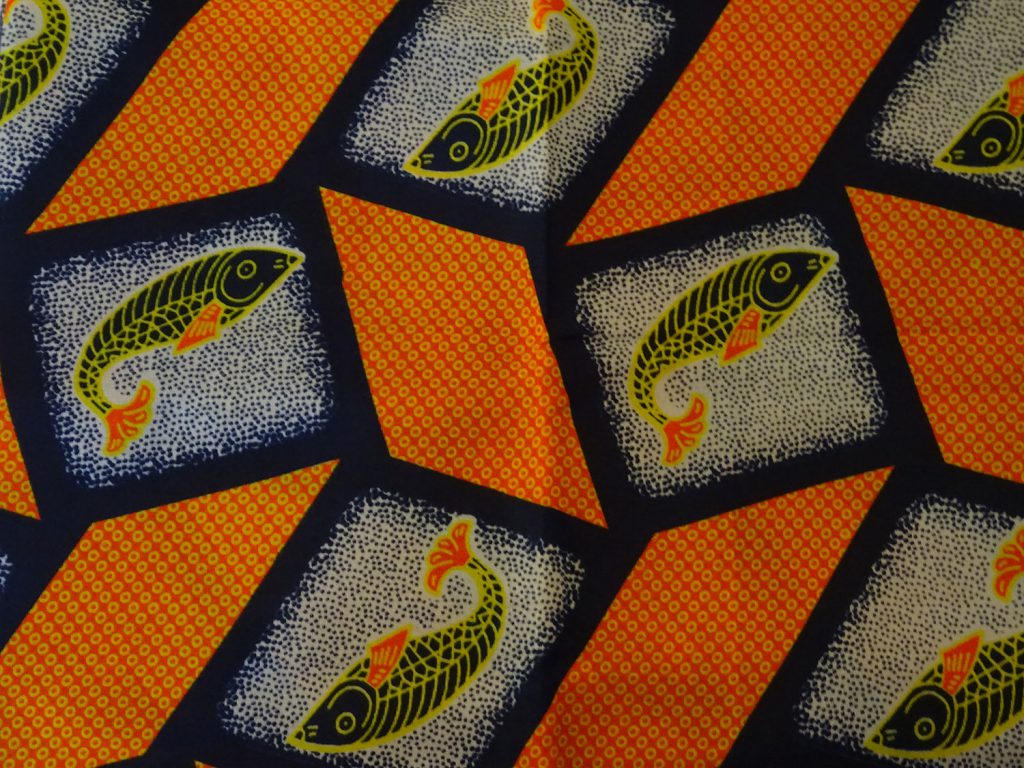 Orange capulana cloth decorated with fish.