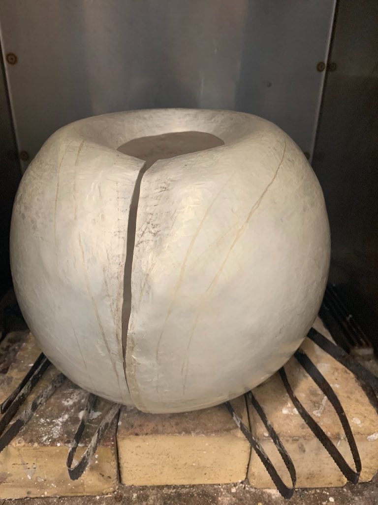 The sculpture is now more rounded, almost spherical. There is now a clean cut down the middle with a slight opening. 