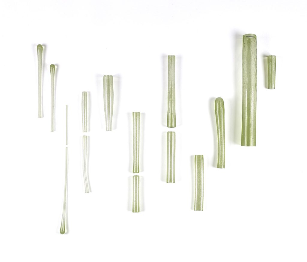 Green glass tubes arranged in lines against white.