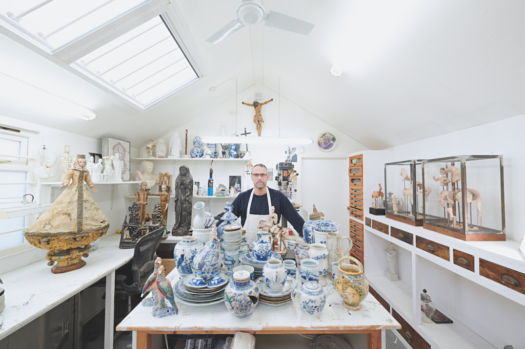 A man in a studio surrounded by porcelain pieces.