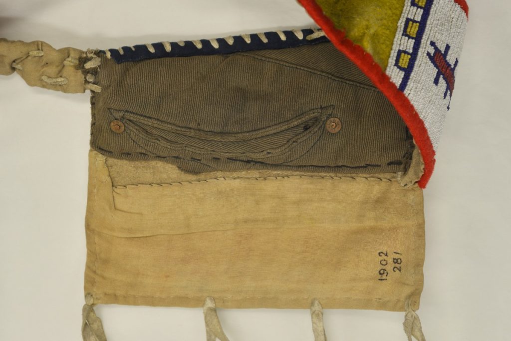 Navy green jeans woven into a roughly square area of light yellow leather, with colourful beadwork on a folded section.