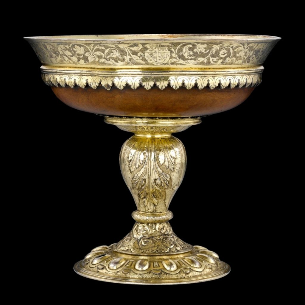 Wide wooden bowl with a ornate gold-coloured metal rim, standing on a candlestick-like golden stem.