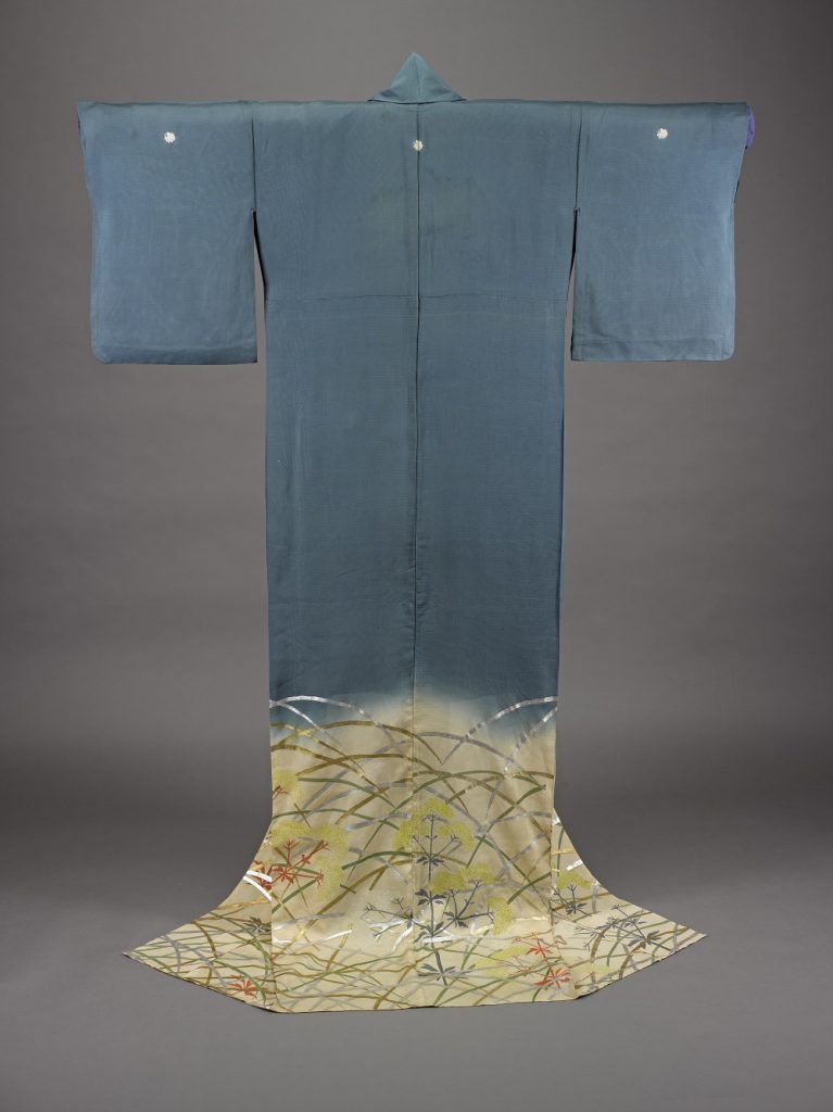 Back of a hazy blue robe hung on a stand as though being worn. Yellow floral pattern from knee level down. 