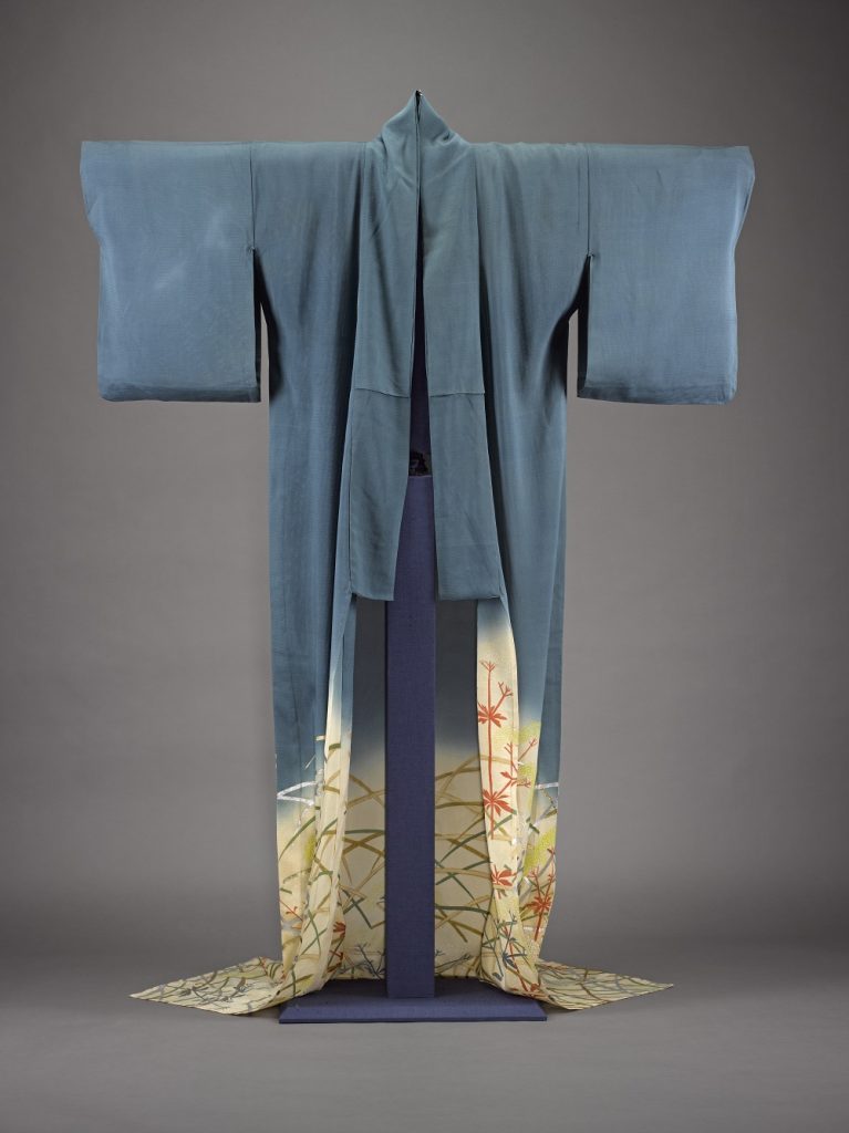Hazy blue robe hanging on a stand, sleeves held up. Blue gives way to yellow floral pattern at the bottom, which is open.