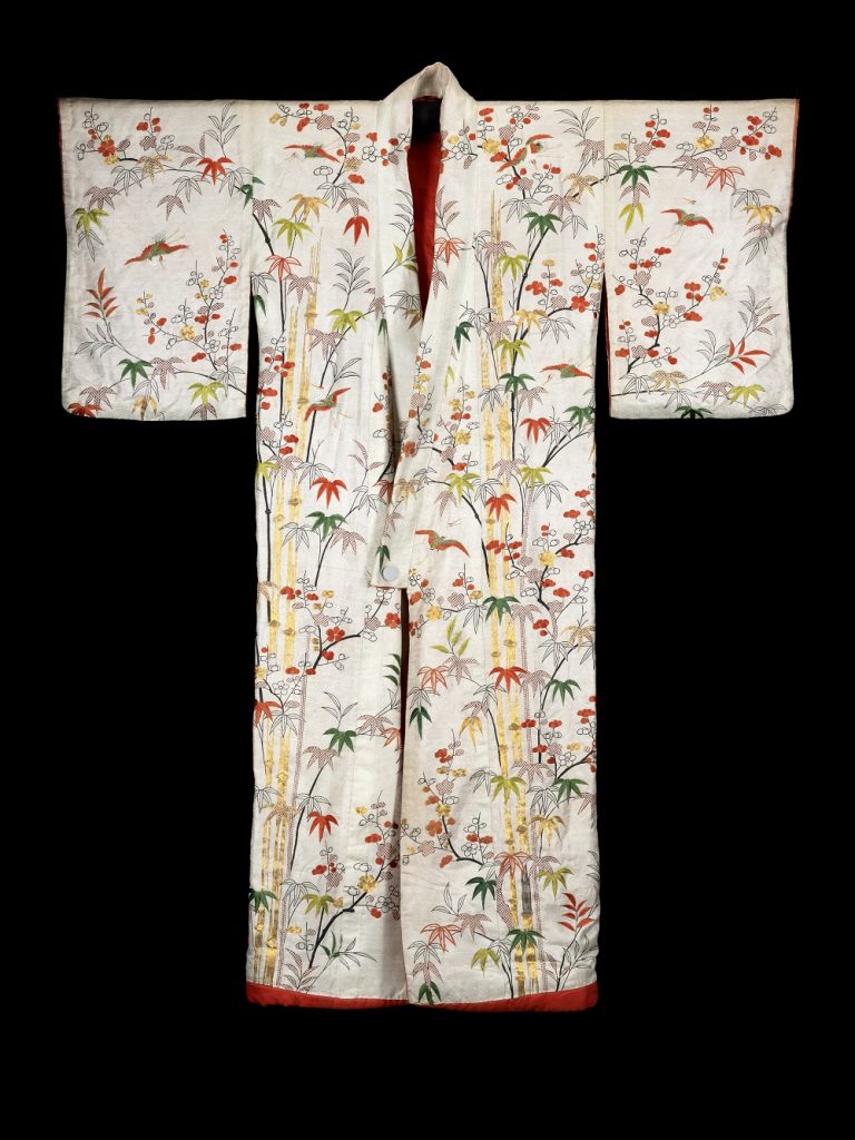 White robe against a black background. Red, green, yellow and purple leaves grow on dense patterns of bamboo shoots.