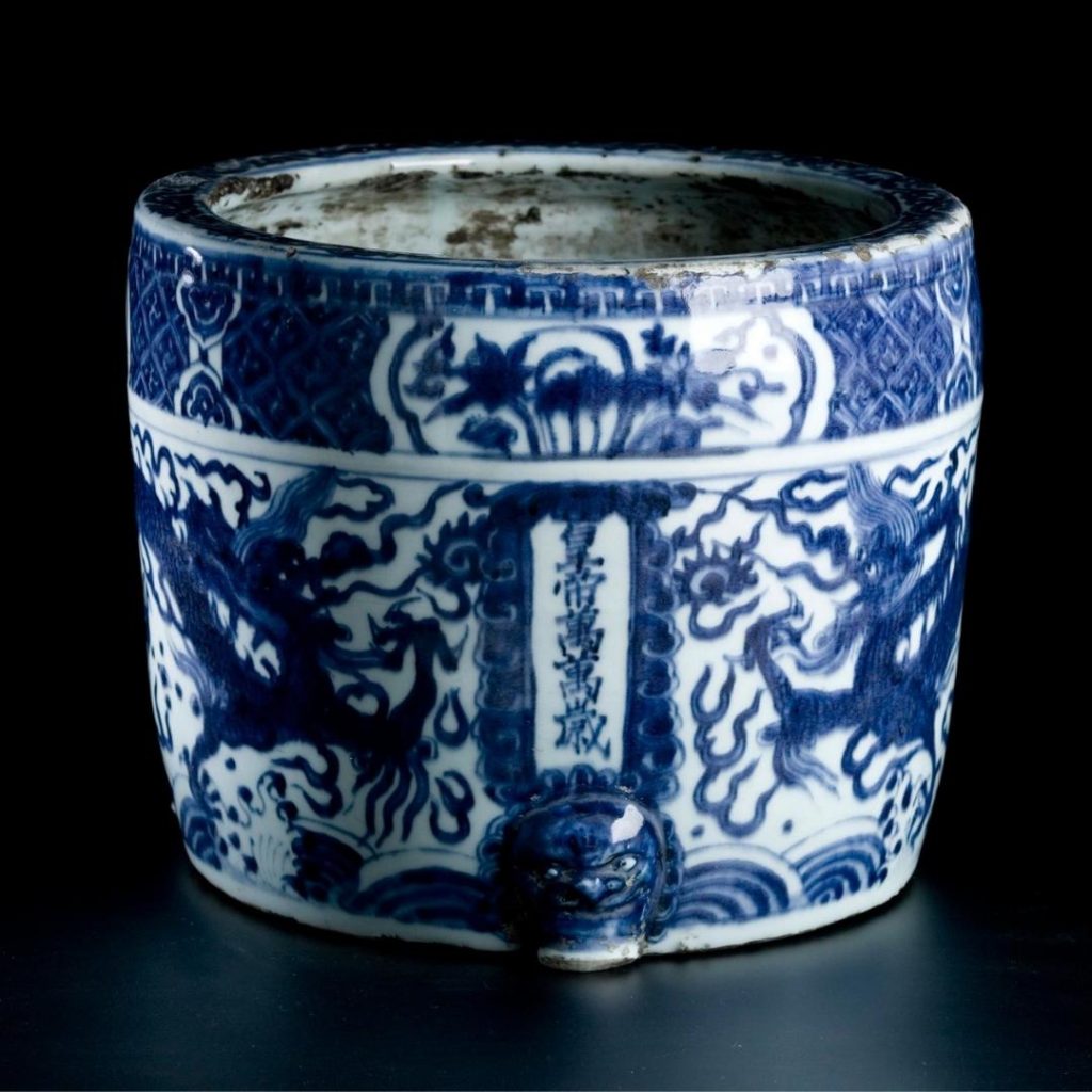 Mug-shaped blue and white incense burner with dark blue dragons, Chinese hieroglyphs, and a geometric pattern along the rim.