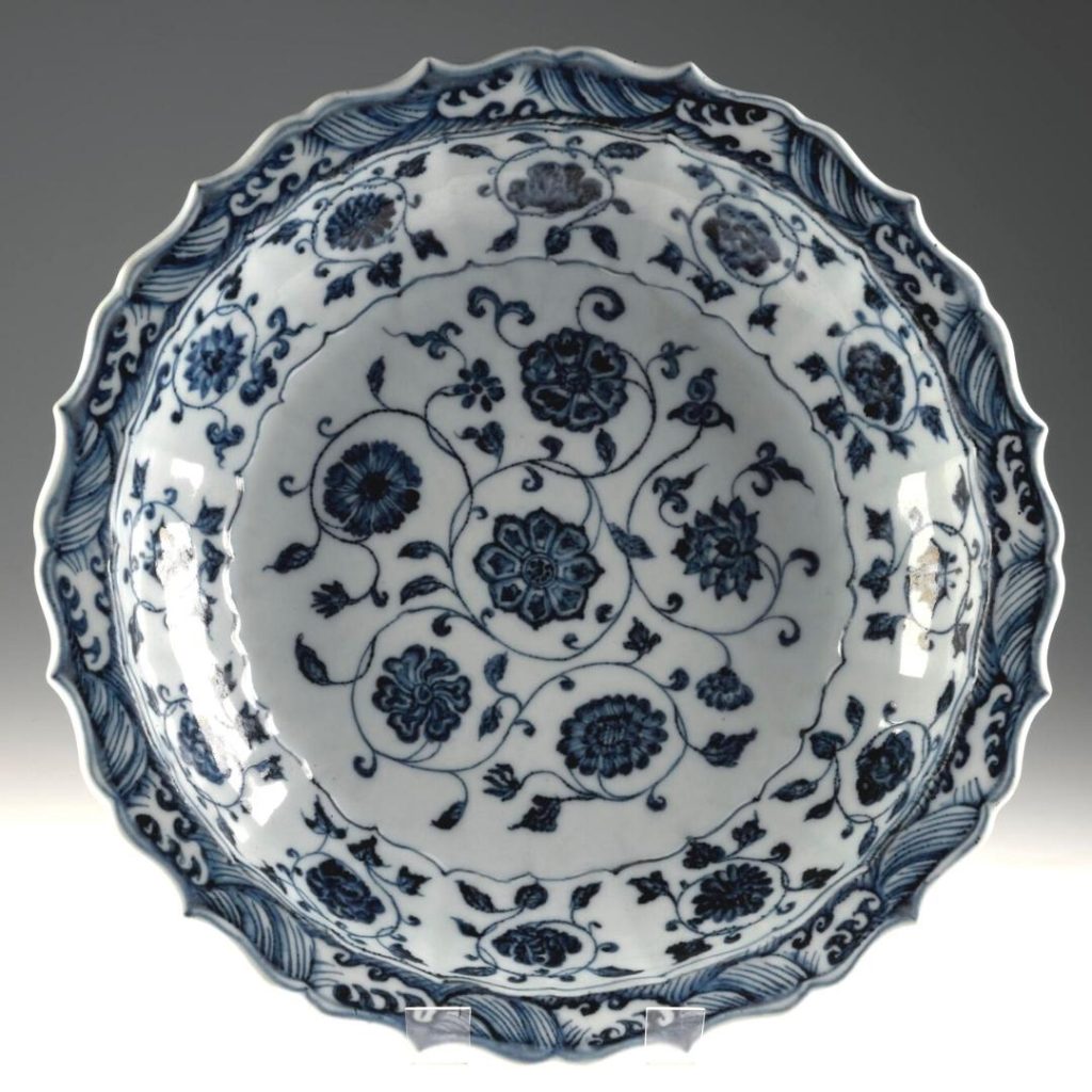 Round blue and white plate with tiny points like a flaring sun. Thin, dark blue flowers in the centre and in a ring around the centre.