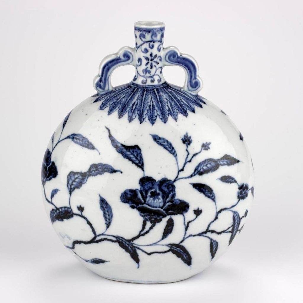 Spherical flask with a narrow spout, decorated by blue flowers on a white base and blue leaves under the spout.