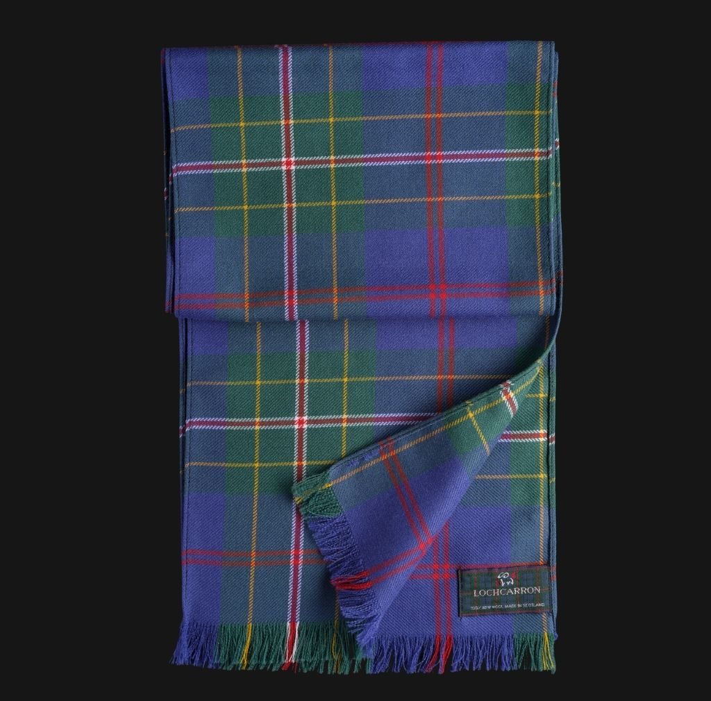 Tartan scarf on a black background laid out vertically. Tartan has a blue base with red and white strips, yellow lines and green squares.