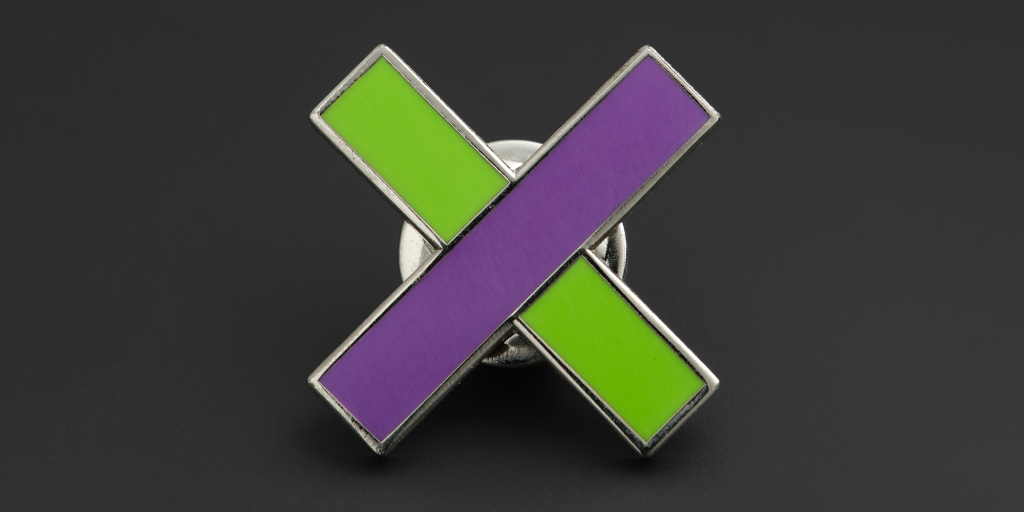 A pin in the shape of a green and purple cross.