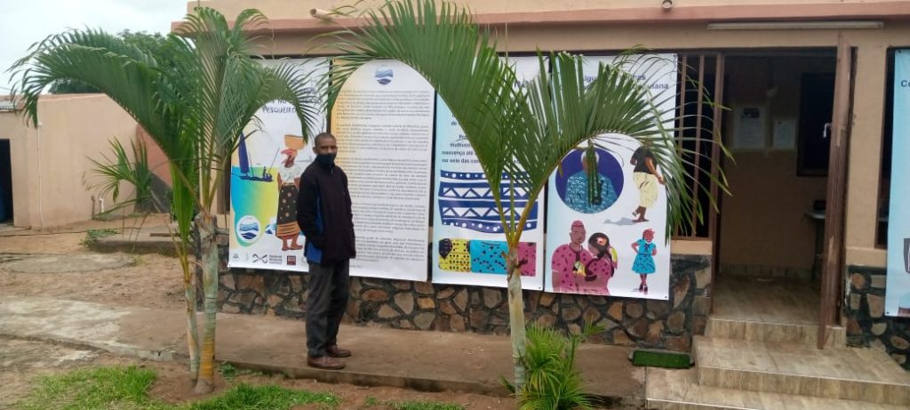 Man stands in front of a large information panel on a wall next to small palm trees.