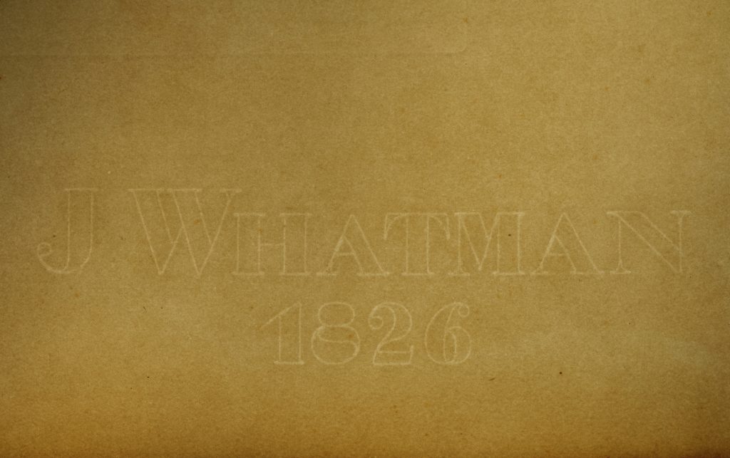Colour photo of a watermark on sepia coloured paper.