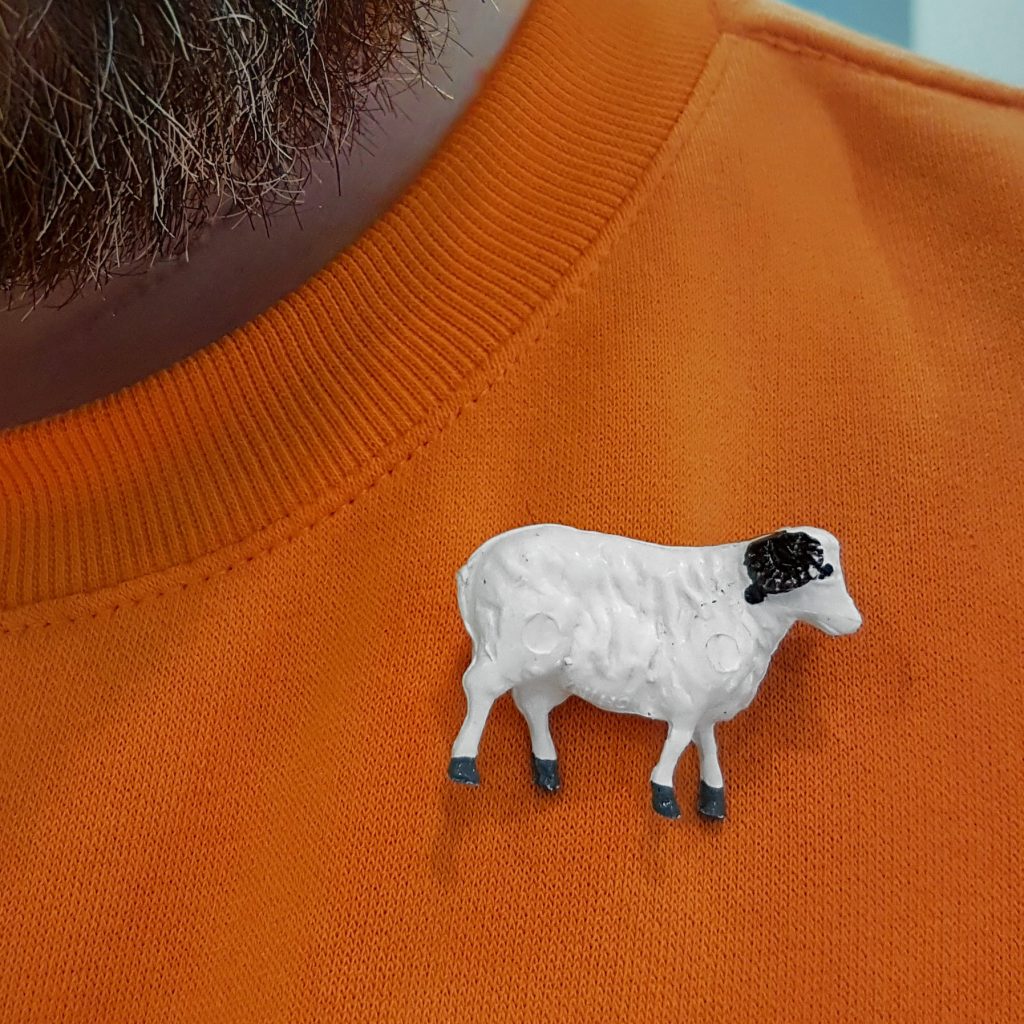 A sheep brooch on an orange jumper.