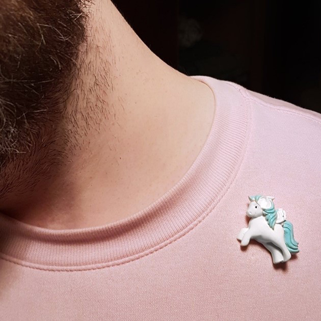 A white my little pony style brooch on a pink jumper.