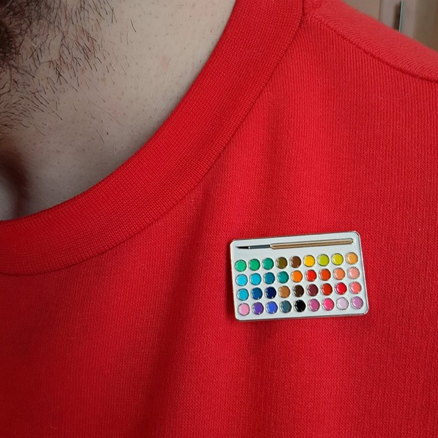 A colour palette pin against a red jumper.