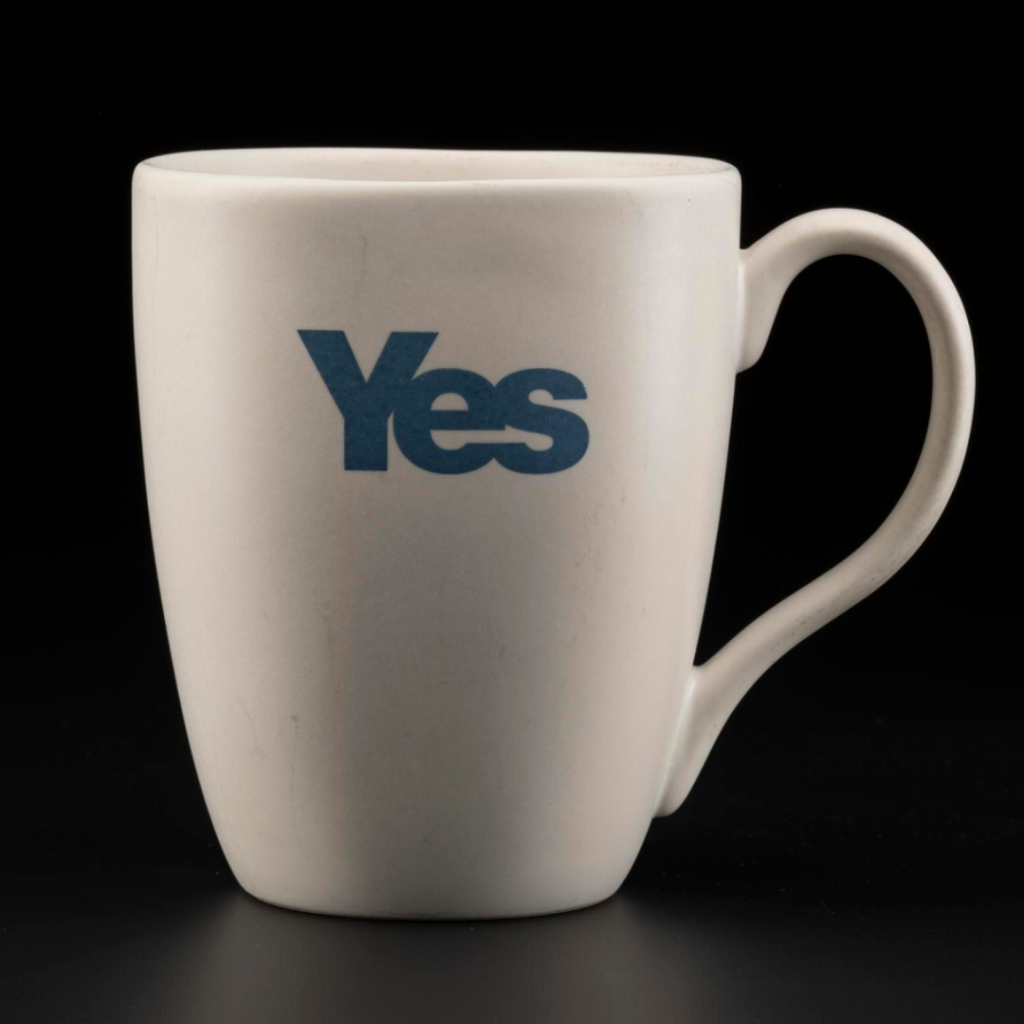 Simple white mug, tall but not overly so, with an earlobe-shaped handle and the word 'YES' written in indigo blue sans-serif font.