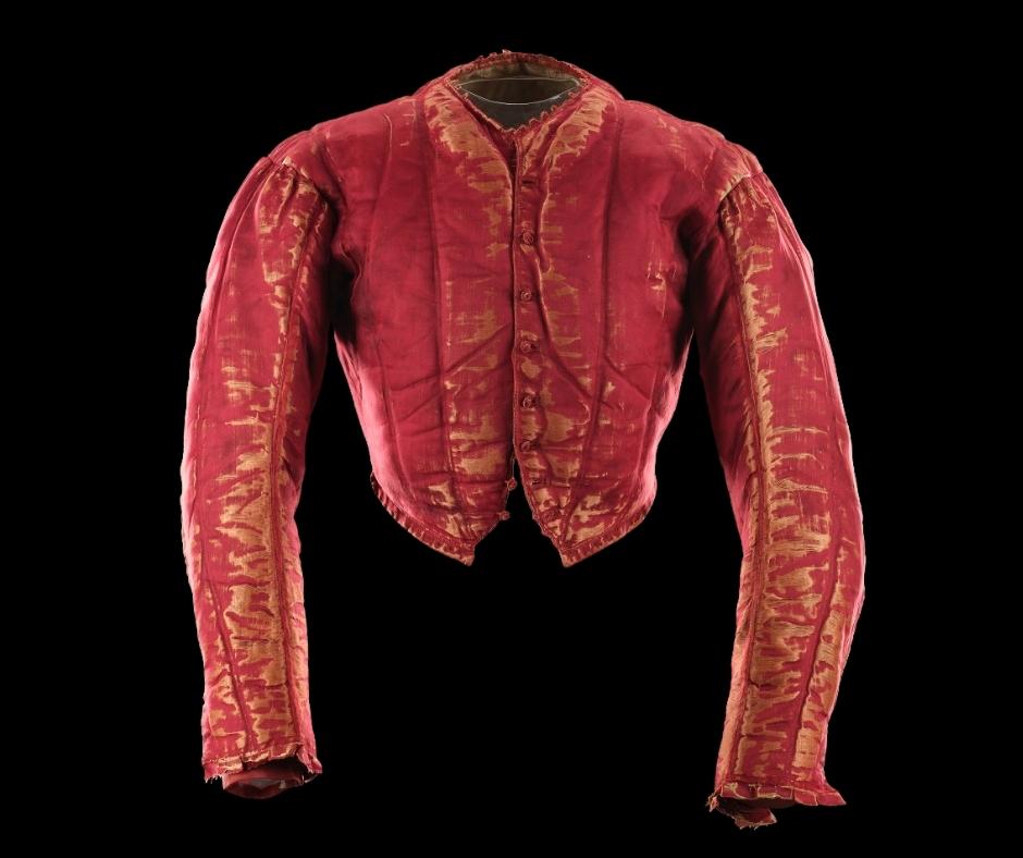 Red doublet on its own against a black background. Silky red texture with golden thread details on the sleeves, middle and collar.