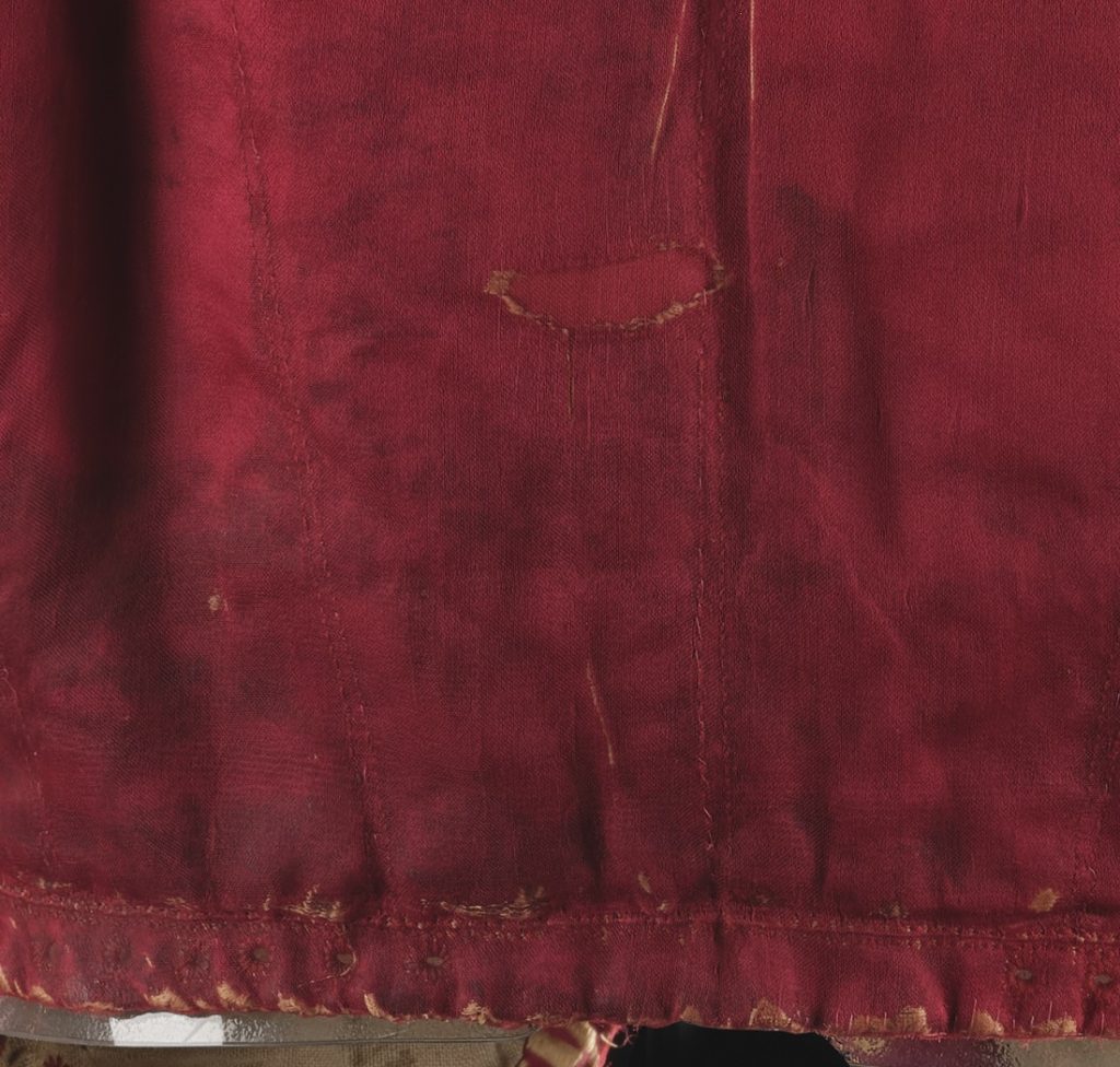 Closeup of a section of the red doublet with stitching over a damaged section.