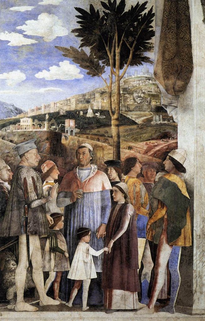 Renaissance painting of a group of nine men, a woman and two children all in colourful clothes. A fortified, terraced town rises up in the background.