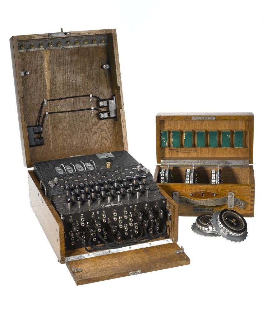 Enigma machine housed in wooden case with four code rotors, and a wooden case containing five spare rotors.