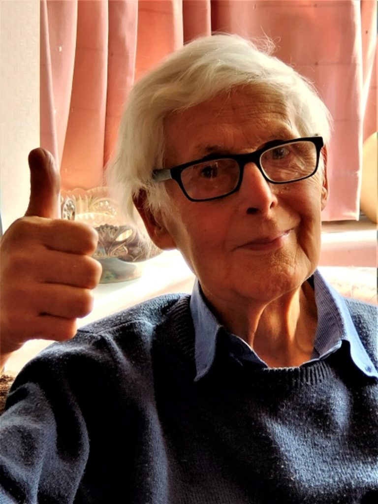 An elderly gentleman smiling with his thumbs up.