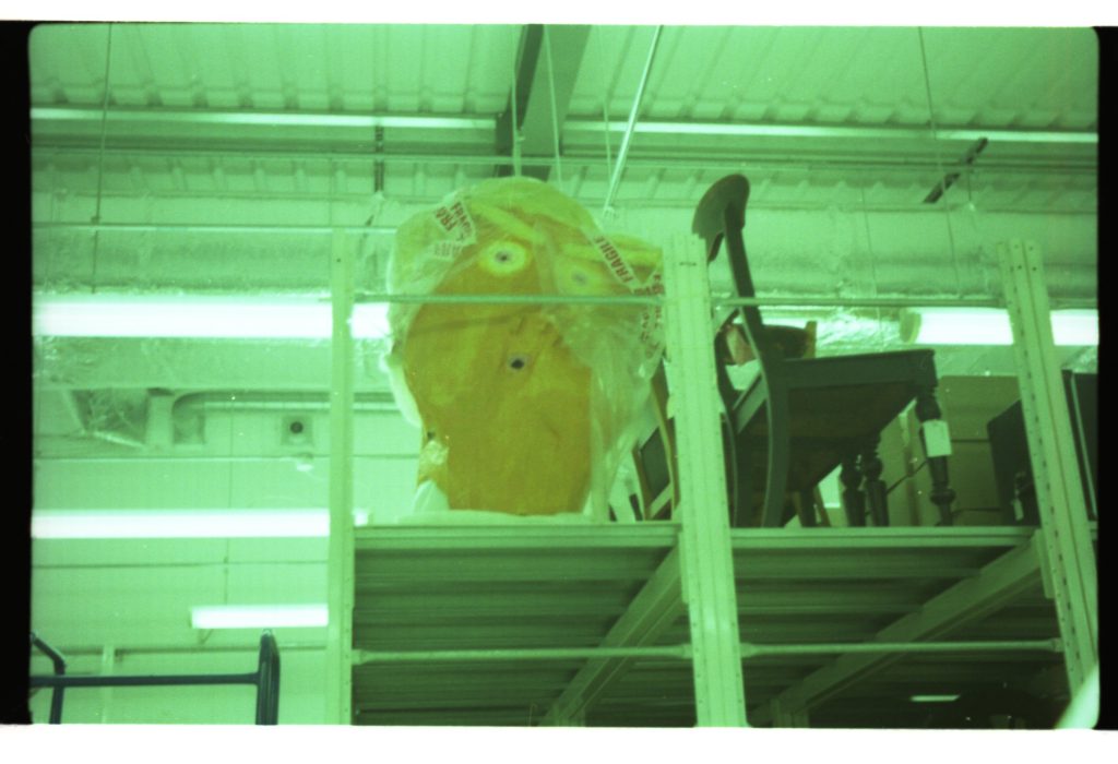 Colour photo of a large cartoon papier mache head.