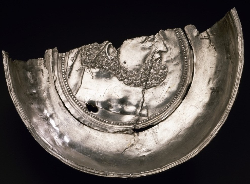 Deep, shiny silver dish sliced lengthwise in half. Two-thirds of Hercules' head is shown in the middle.