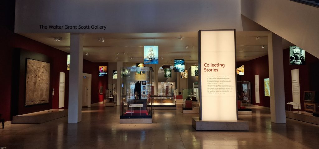 Overview image of the Collecting Stories gallery at the National Museum of Scotland, with various cases and info panels, none of which are clearly visible.