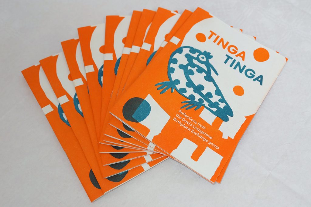 A brightly coloured pamphlet in orange and teal with the words Tinga Tinga at the top. On the pamphlet it says "Reflections from the David Livingstone Birthplace Exchange group".