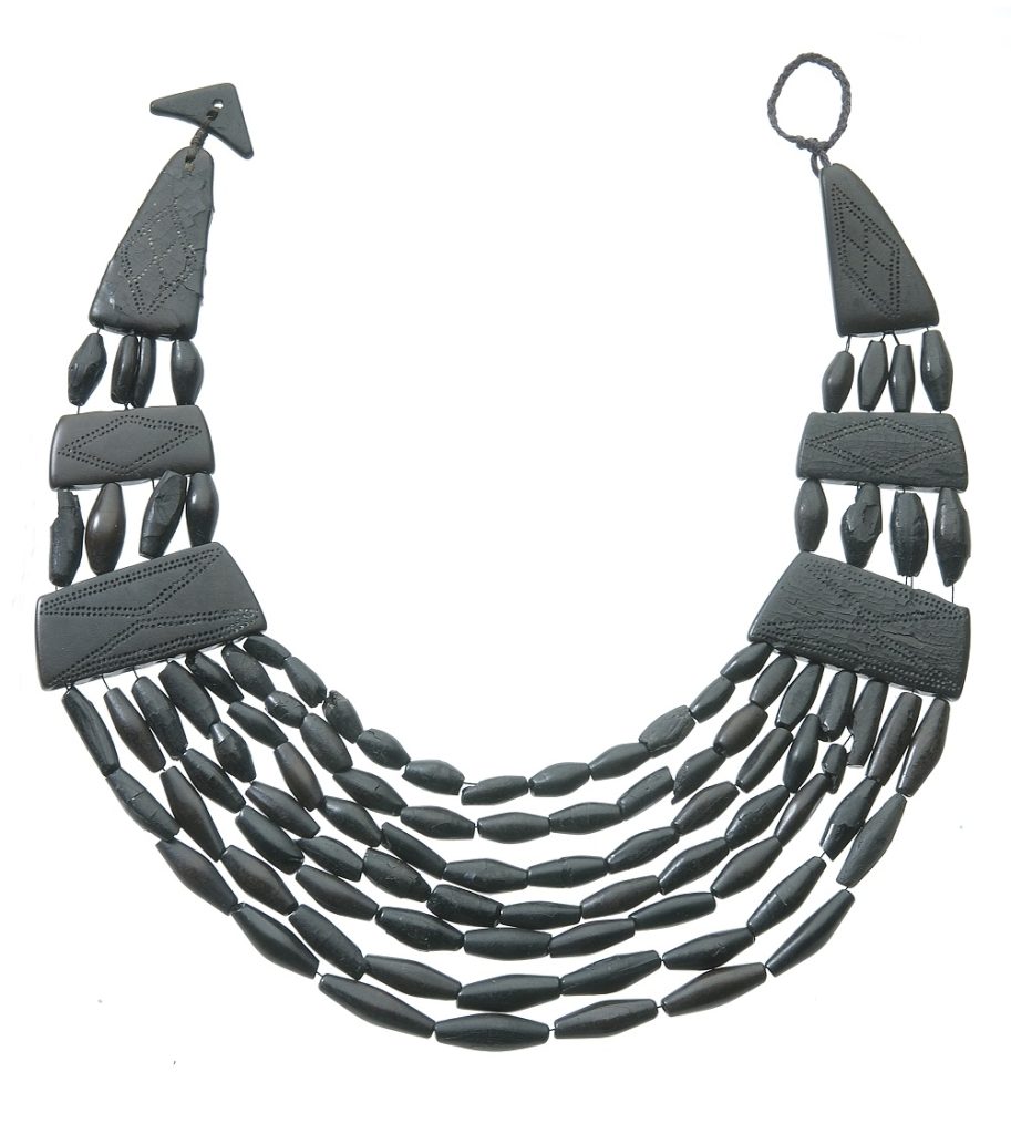 Black jet necklace with six broad spacers and seven strands of beads. The spacers have diamond patterns pecked onto their surface.