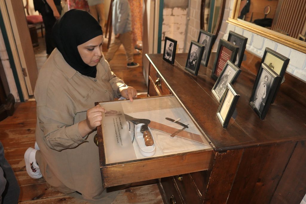 A woman wearing a hijab kneeling in front of a display on the SS Great Britain.