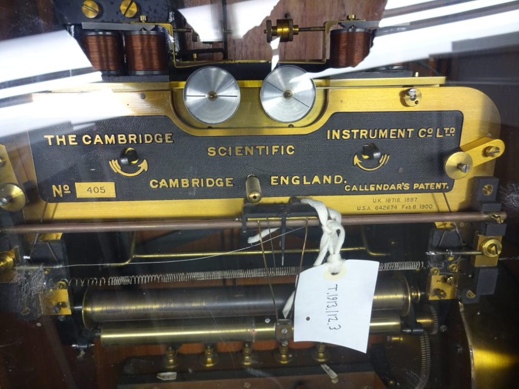 Black metal and brass machinery with springs and coils.  The words "The Cambridge Scientific Instrument Co" is on the machine.