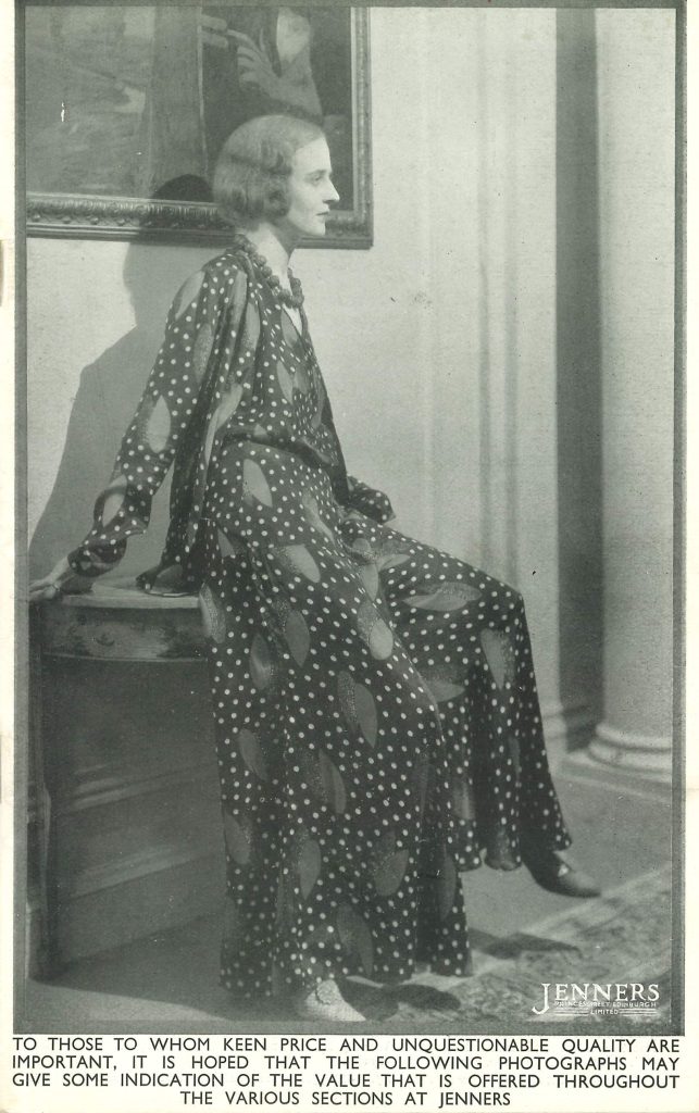 Jenners catalogue page from 1931 in black and white, showing a woman in a loose, spotted dress sitting on a small desk beneath a framed painting.