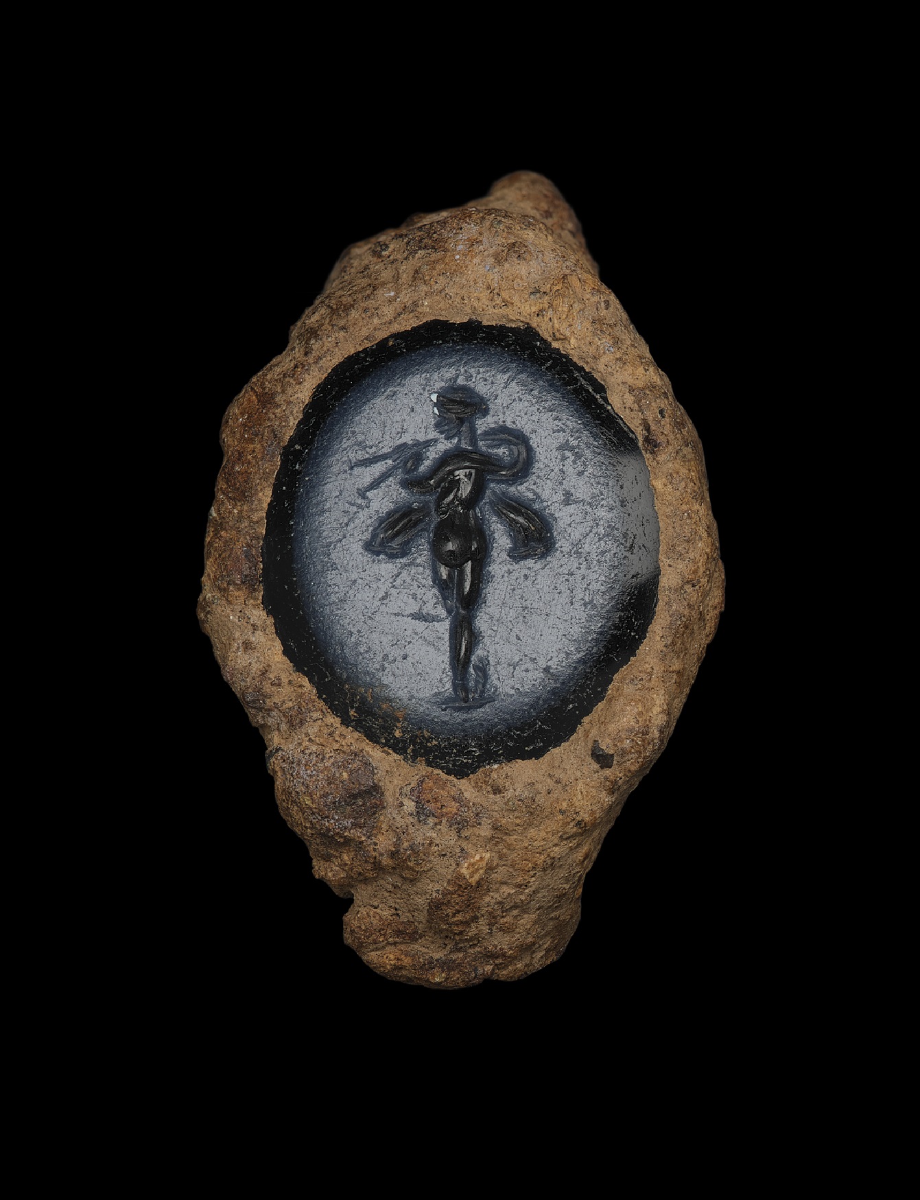Within a heavily rusted ring-like setting is a tiny portrait of a goddess, standing upright and nude with what looks like wings. She stands within a pale blue area ringed by dark blue.