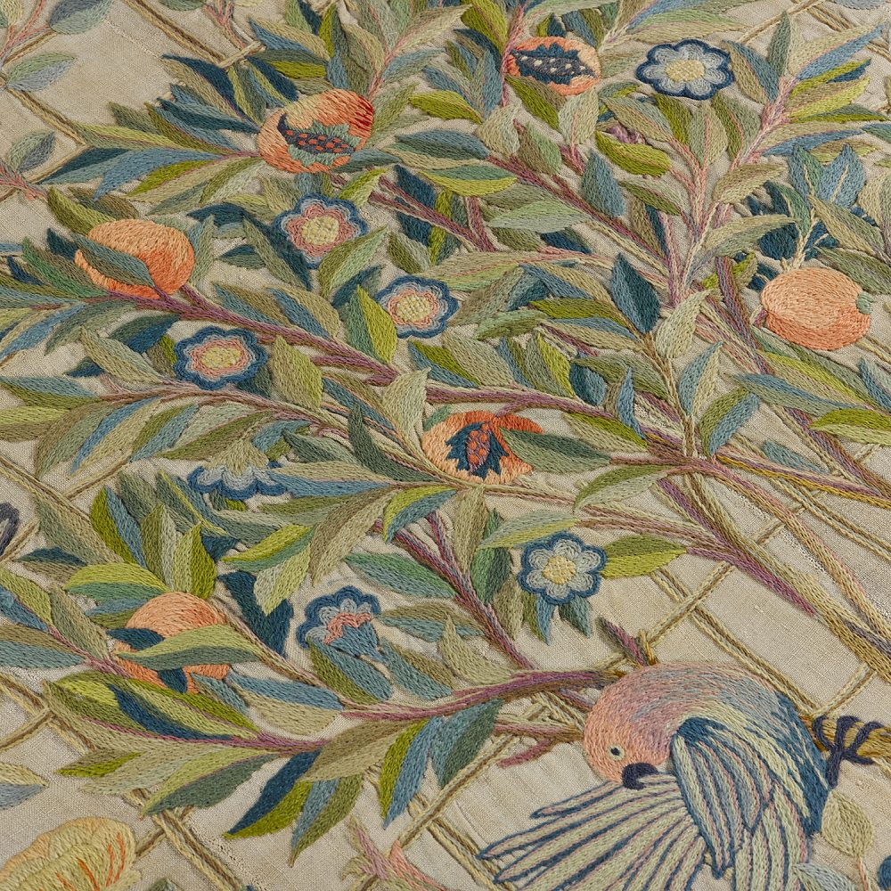 Close-up of embroidered wool on linen of a pomegranate tree and birds.