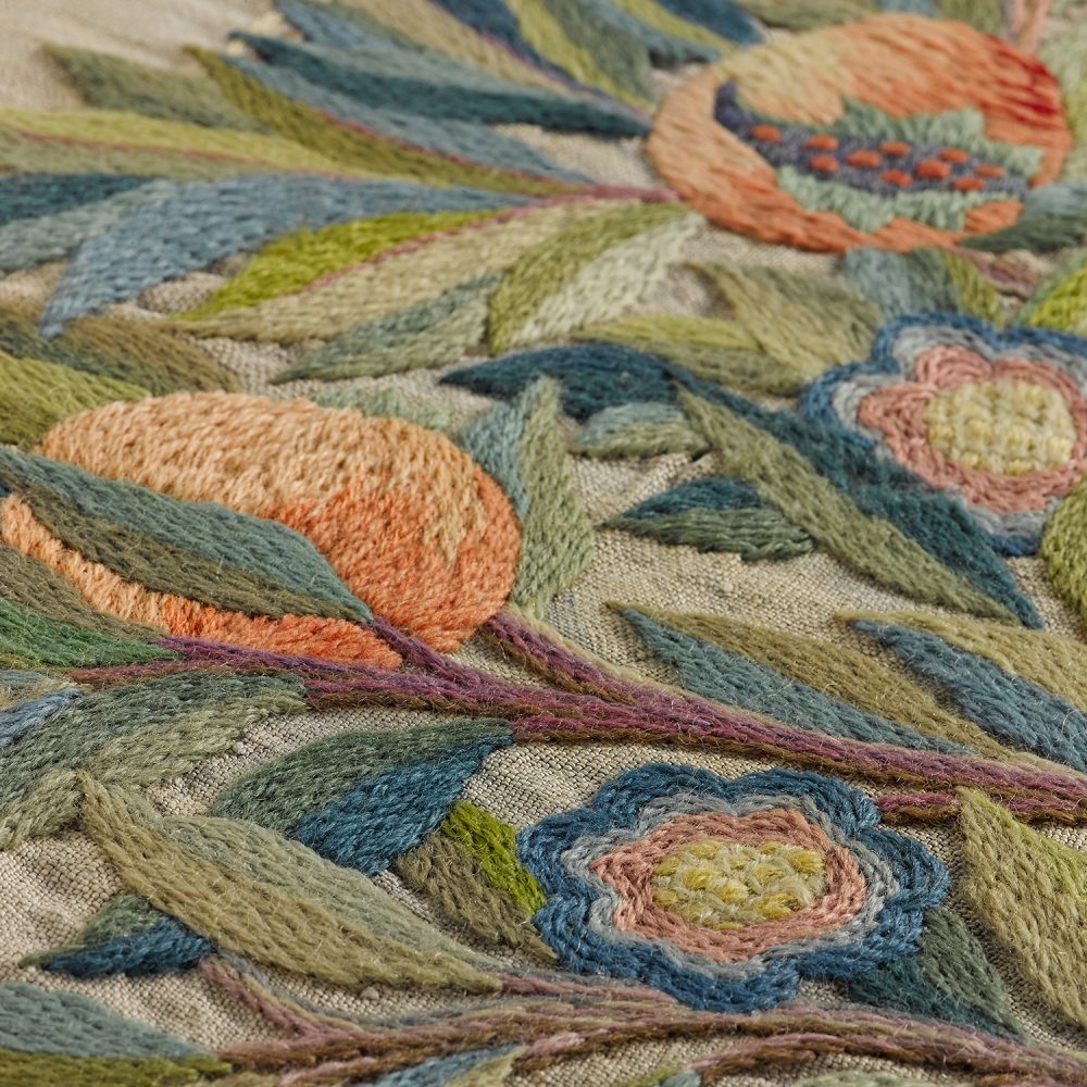 Close-up of embroidered wool on linen of a pomegranate tree.