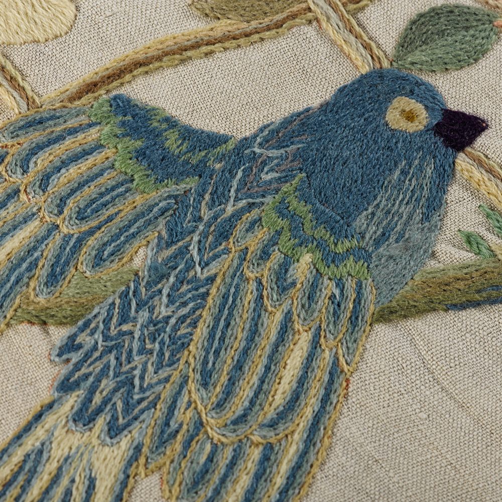 Close-up of embroidered wool on linen of a bird.
