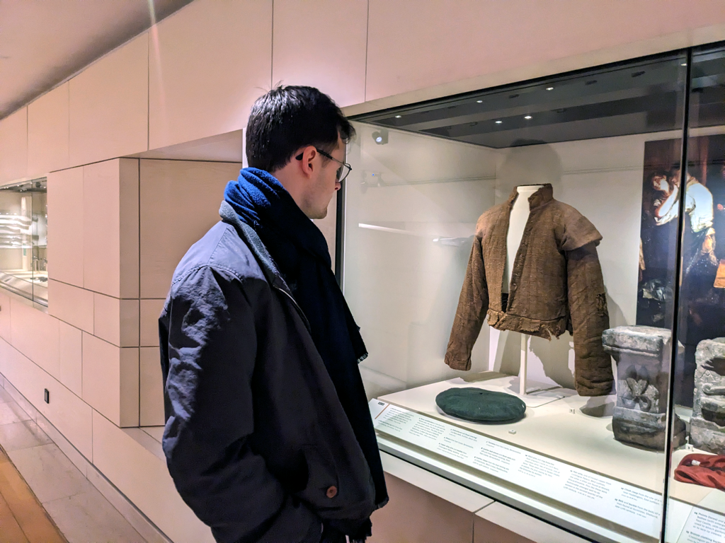Joe stands with his back to the viewer as he looks into the museum case that houses the doublet.