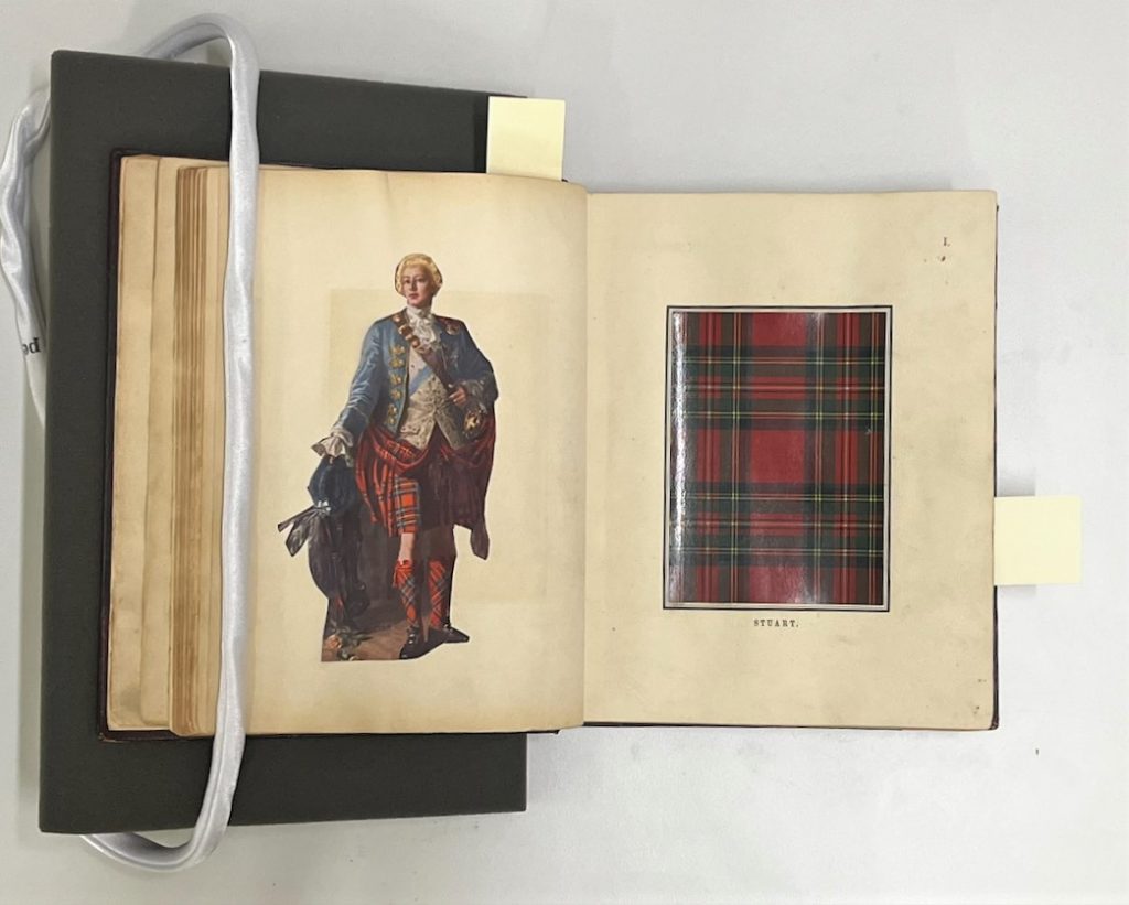 An open book, weathered and yellowed with time, shows a swatch of red and green tartan on the right page, and an aristocratic figure in a blue jacket and the same red-green tartan kilt on the left.