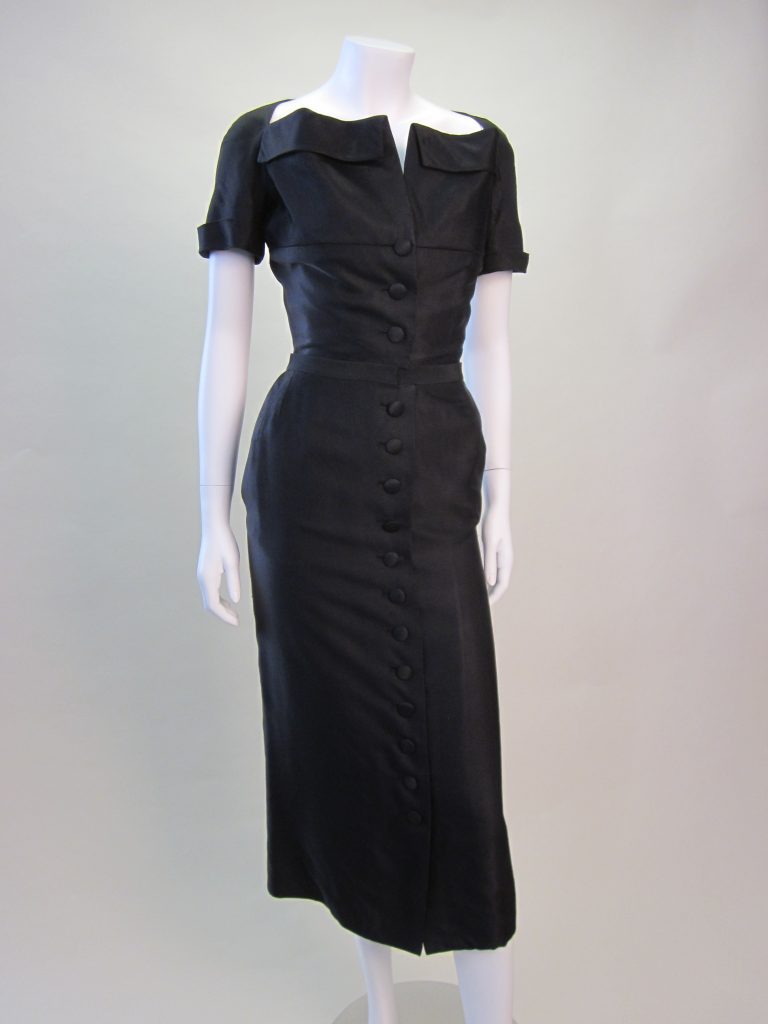 Black, narrowly corded, silk-faille ensemble, comprising bodice and 2 separate skirts, one narrow and one wide. Bodice with a wide neckline and fold-over collar, and 3 self covered buttons, lightly boned with tulle inner corset section fastened to the front with hooks and eyes. Large woven label, \'Christian Dior, Paris, 02195\' with hand written ink label to reverse, \'72081\'. Two interchangeable skirts, in matching silk, one narrow with 12 self covered buttons fastening CF, and one circular with 4 buttons to fasten at side hip. 