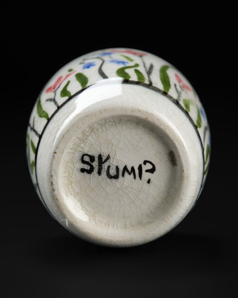 Circular bottom of a cream-coloured ceramic egg cup with the word “Stump” painted in black.